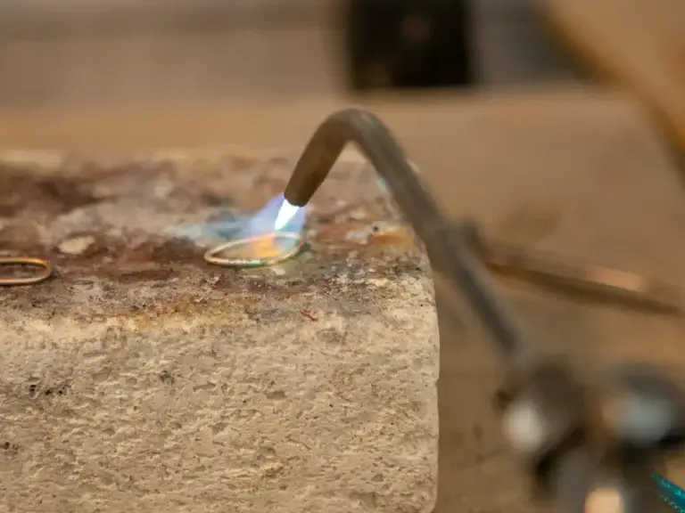 Silversmith soldering a handmade silver ring with a torch during a silver class in Kuta, Bali
